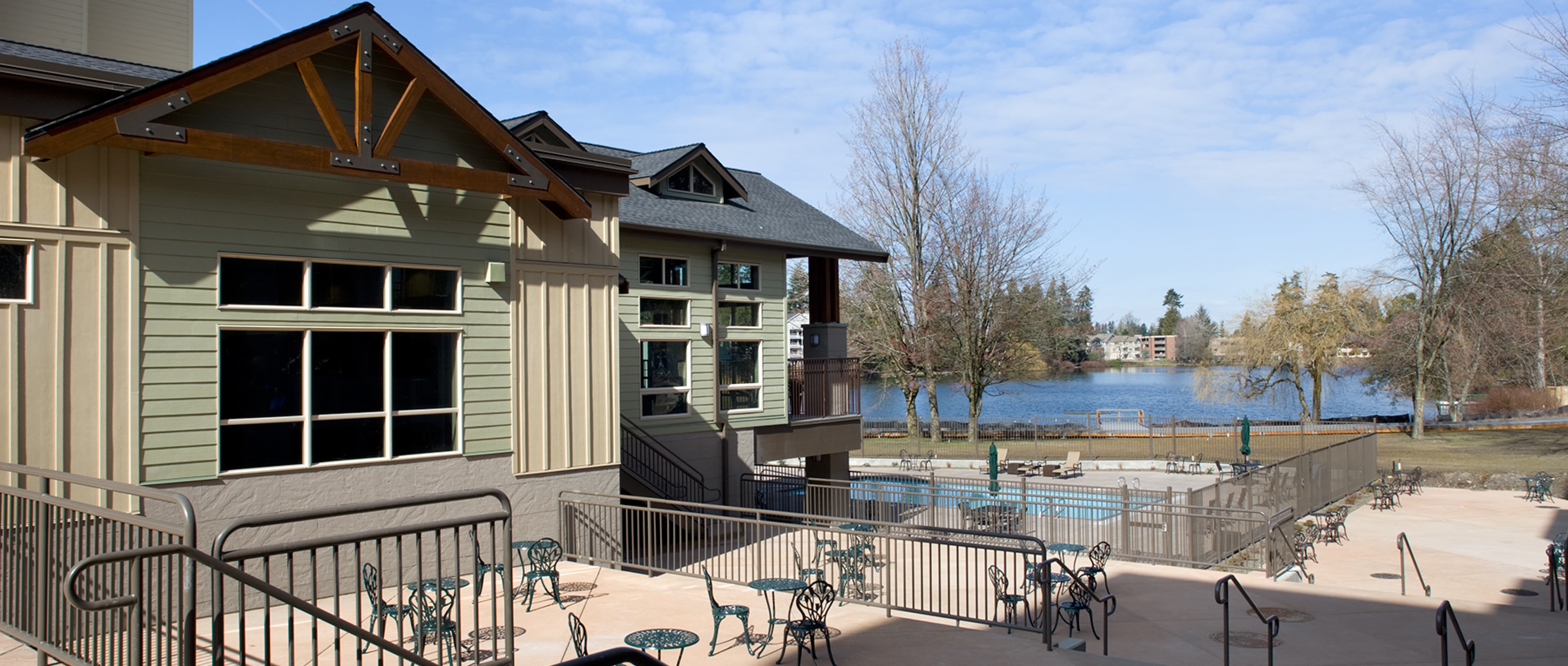 Concrete Patios with black metal railings,chairs and tables with the Echo Lake Apartment building off to side and lake in background